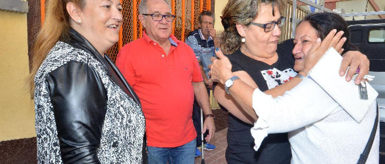 Inmaculada González y Nino Díaz, dos de los premiados, observan cómo Josefa Macías, de blanco, se abraza con otra vecina.