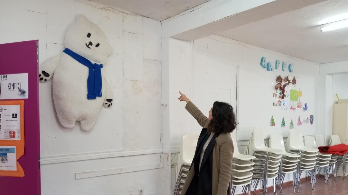 La directora señala las humedades en el aula de cine.