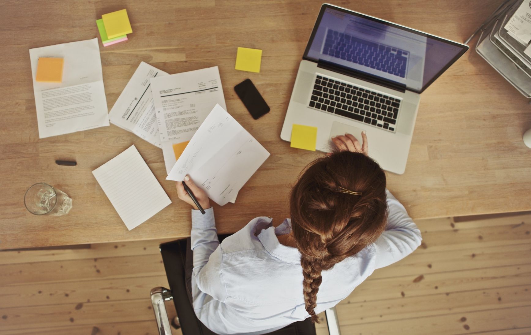 Businesswoman working at her office desk with documents and laptop