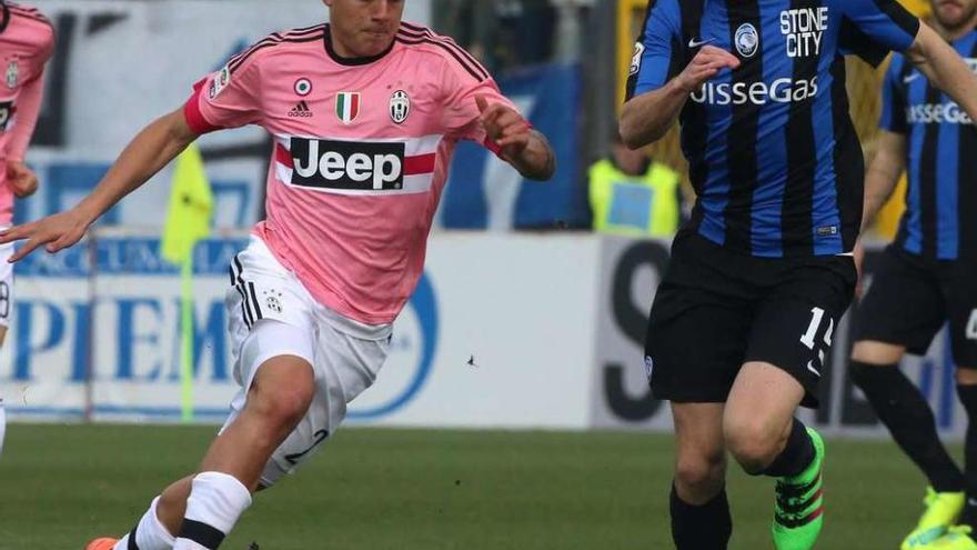 Dybala conduce el balón en el Juve-Atalanta, con el equipo turinés luciendo camisetas rosa. // Paolo Magni