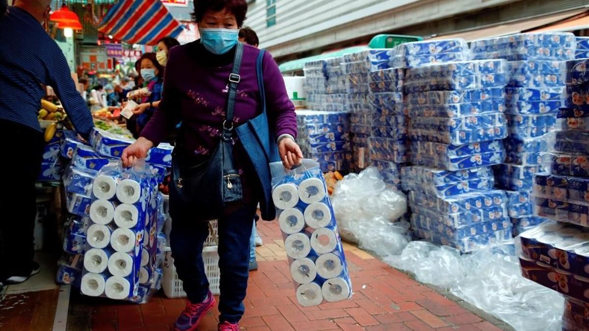 Una mujer compra papel higiénico protegida con mascarilla por temor al coronavirus en un mercado de Hong Kong