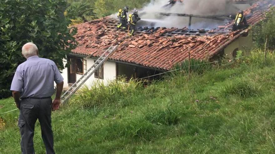 Un vecino observa las labores de los bomberos para apagar el incendio de la vivienda en El Cobayón (Piloña).
