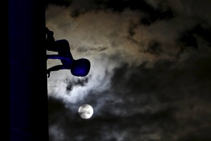 A supermoon is seen in the sky next to a statue of a baby in Prague