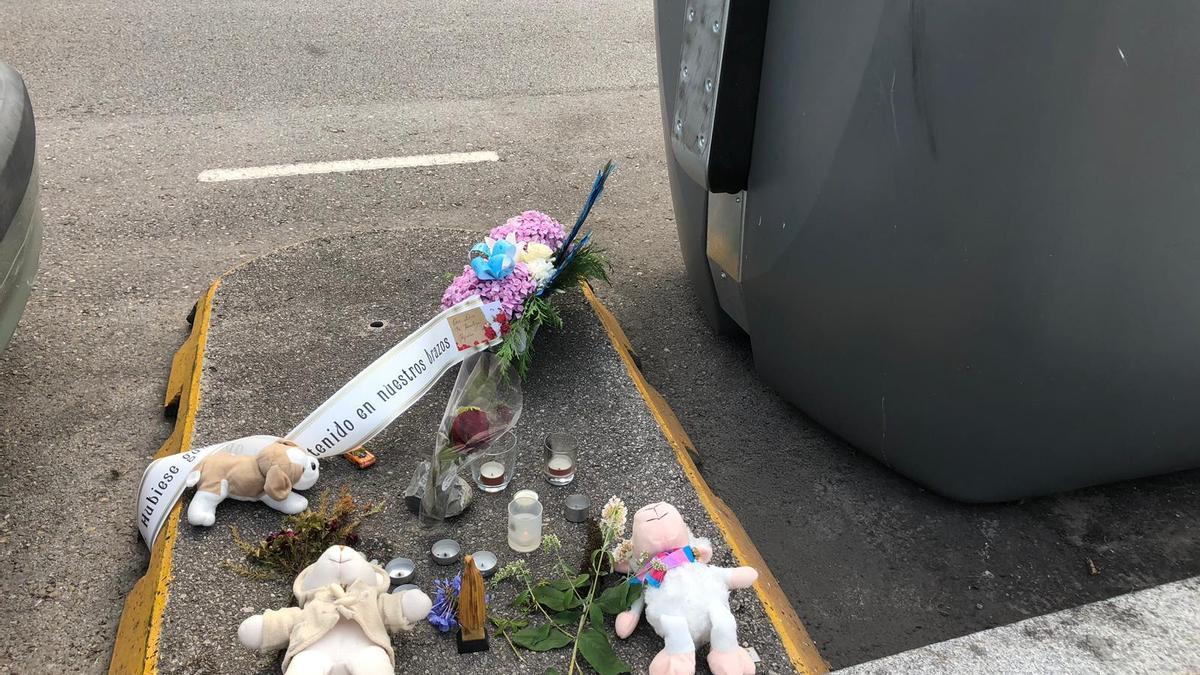 Flores, velas y peluches junto al contenedor de basura en Nuevo Roces en el que apareció el bebé asesinado.