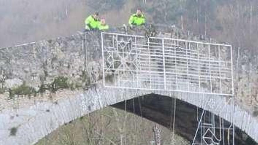 Operarios retirando ayer las luces situadas en el puente &quot;romano&quot; de Cangas de Onís.