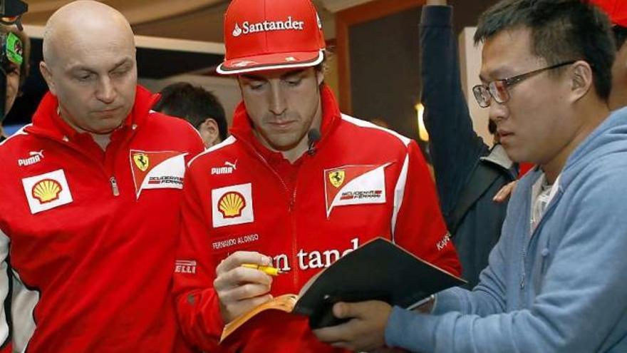 Alonso, firmando un autógrafo a un aficionado chino, a su llegada ayer al circuito de Shanghai.