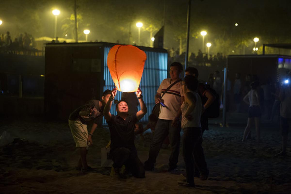 Un hombre eleva un globo de luz al cielo en la playa de la Nova Icària