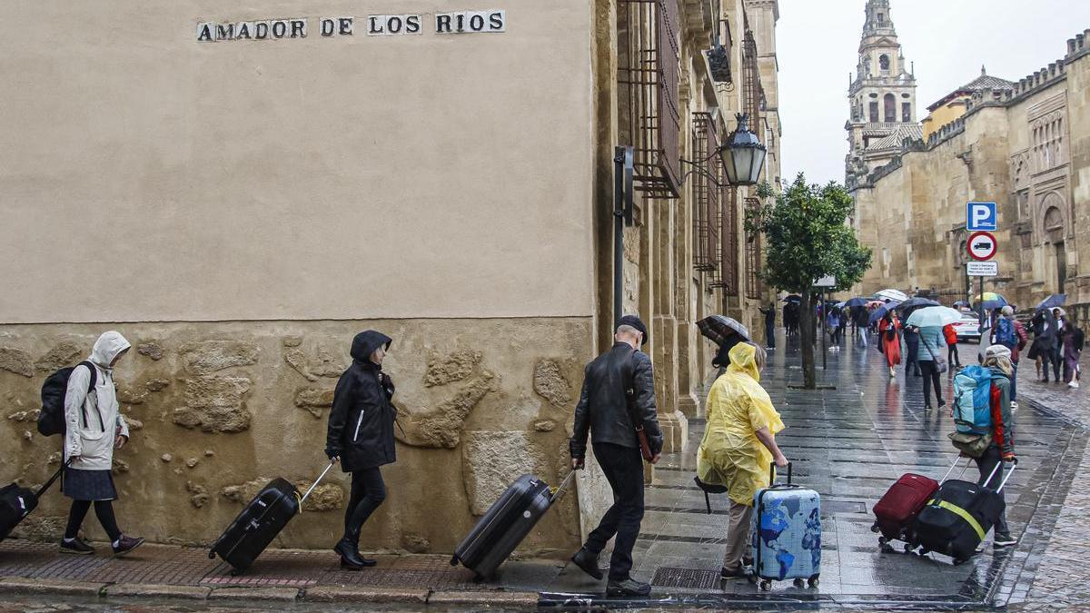 Un grupo de turistas, bajo la lluvia, junto a la Mezquita Catedral.