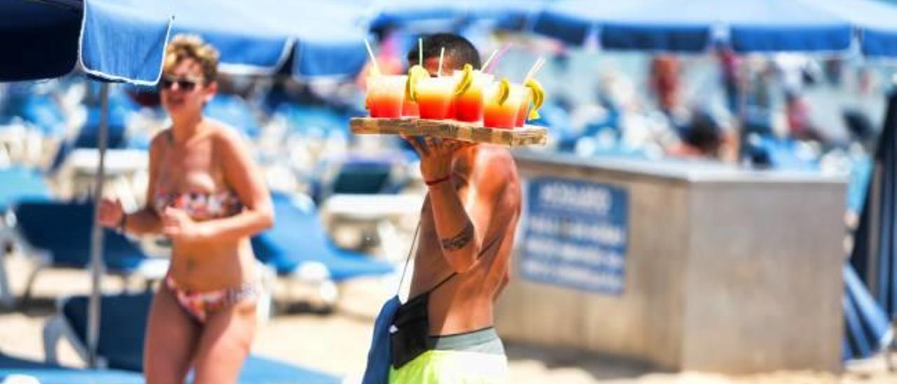 Uno de los «mojiteros» en la playa de Benidorm con una bandeja llena de bebidas.