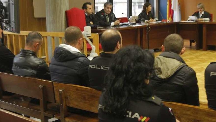 Los tres acusados, de espaldas y escoltados, ayer en la Audiencia viguesa.