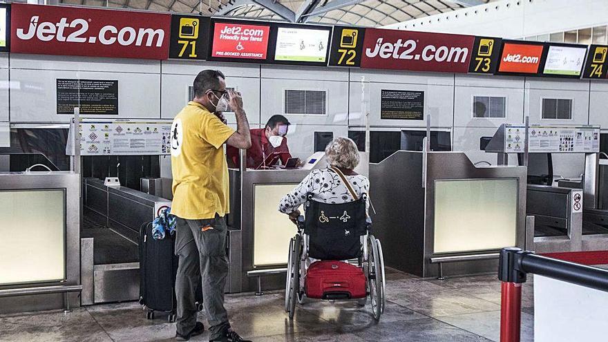 Personal de la compañía Jet2.com atienden pasajeros en el zona de facturación en la terminal del aeropuerto de Alicante-Elche, ayer. PILAR CORTÉS