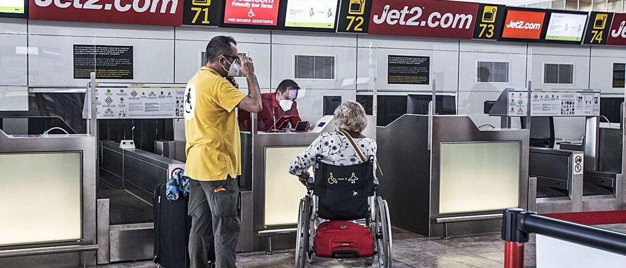 Personal de la compañía Jet2.com atienden pasajeros en el zona de facturación en la terminal del aeropuerto de Alicante-Elche, ayer. PILAR CORTÉS