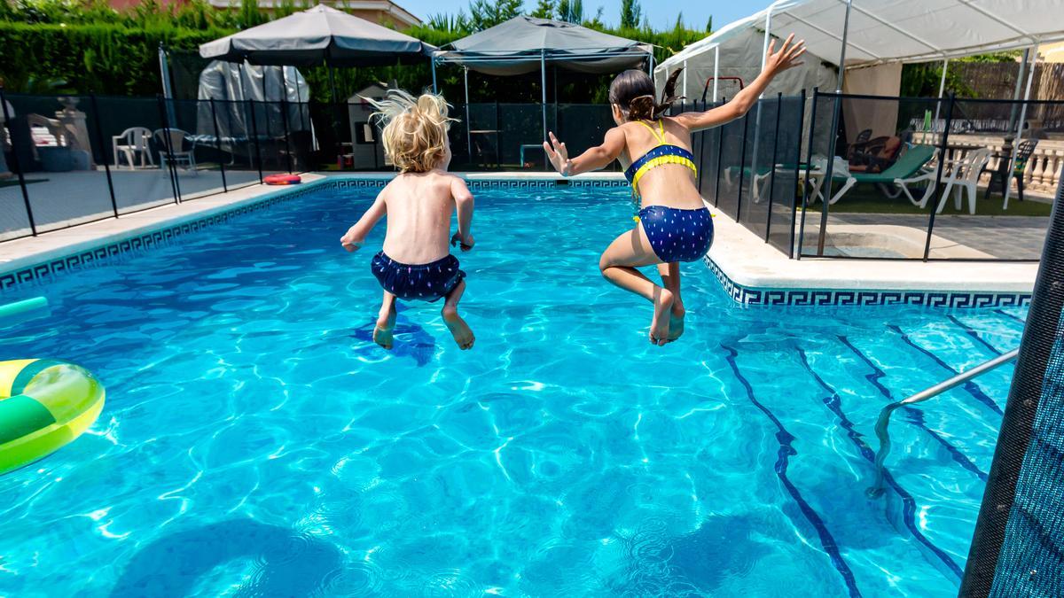 Dos niños lanzándose al agua en una piscina particular.
