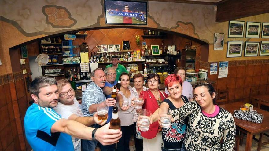 Vecinos de Tuilla brindan por Villa ante una foto del Guaje que preside la barra del bar.