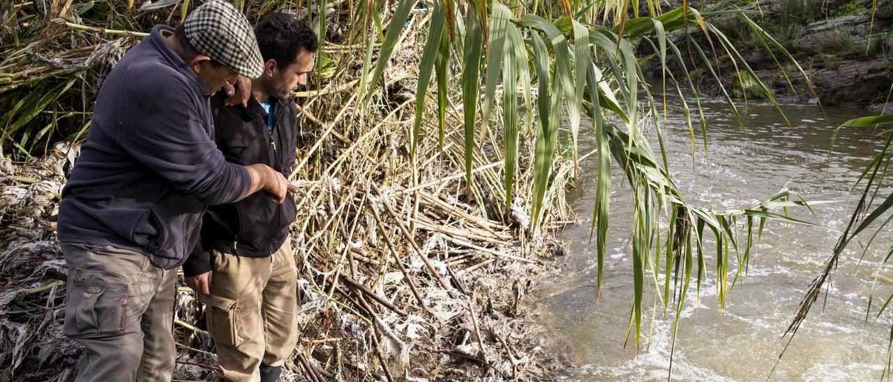 En la orilla, Antonio Leal y Agustín Rebollo muestran la suciedad del cauce. Hace tres días, el agua había anegado unos sesenta metros de terreno.