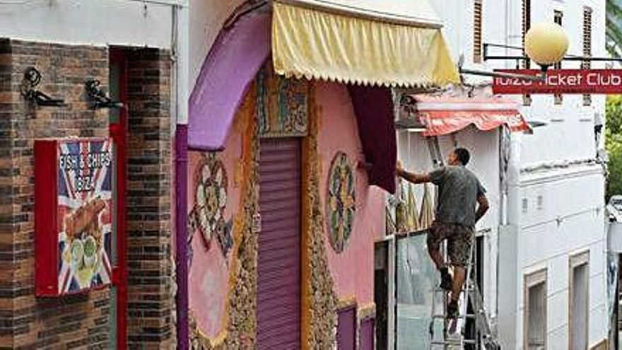 Un hombre retoca la fachada de uno de los establecimientos de la zona del West End, ayer.