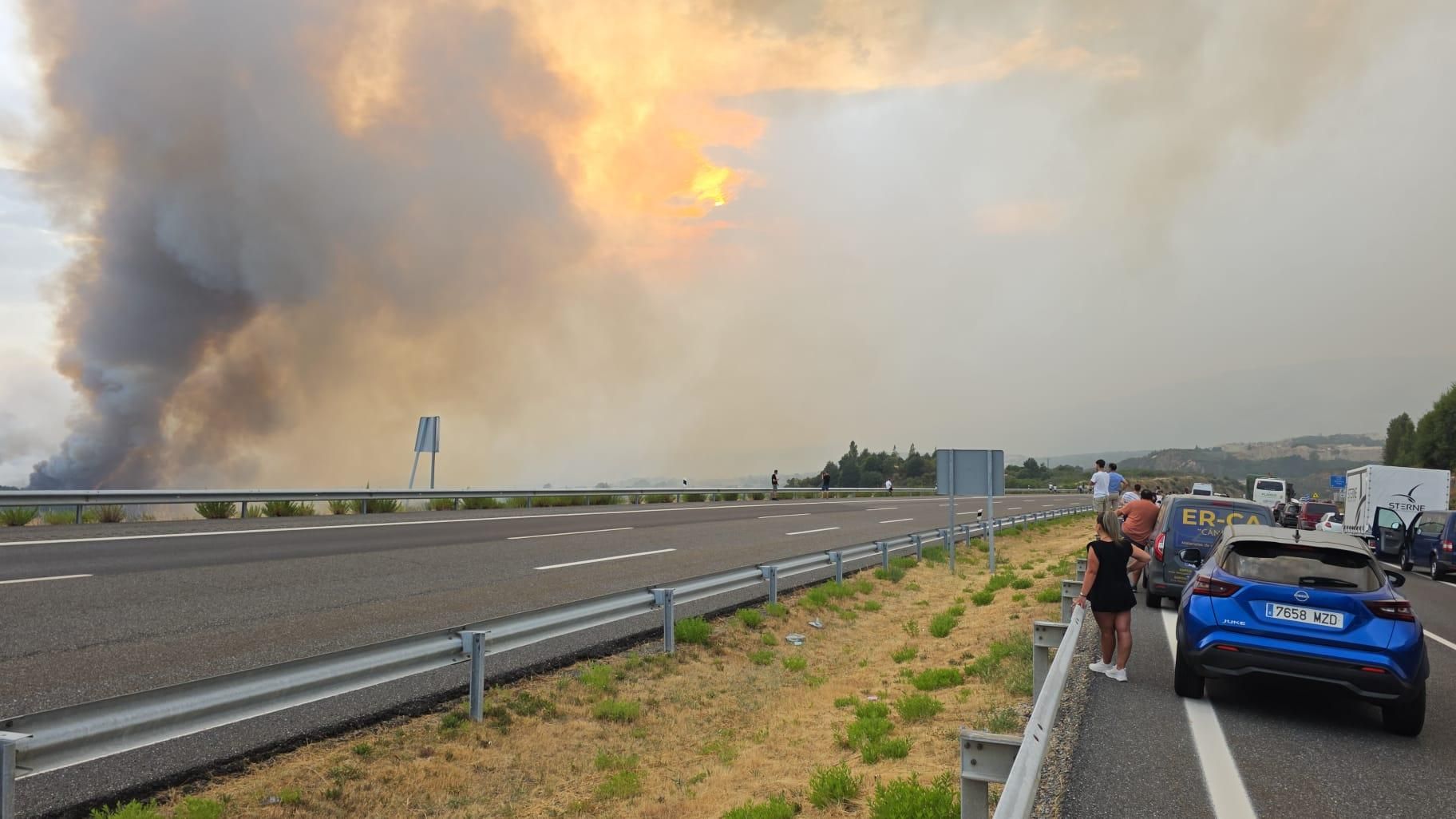 Los ocupantes de los vehículos observan el incendio que acecha la A-52 fuera de sus coches, a la altura de A Mezquita en sentido Vigo