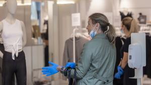 Una mujer se coloca unos guantes proporcionados por el establecimiento al entrar en una tienda de ropa. durante el segundo dÃ­a de la fase 1 del plan de desescalada que ha elaborado el Gobierno de EspaÃ±a. En Sevilla, (AndalucÃ­a, EspaÃ±a), a 12 de mayo de 2020.