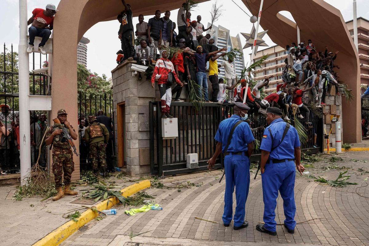 Kenyan police officers stand guard as supporters and mourners of Kenyan opposition leader Raila Odinga gather at the Kenya Parliament in Nairobi on October 16, 2025 ahead of the arrival of Odingas body following his death at the age of 80 during a health visit to India. Kenyan opposition leader Raila Odinga has died at the age of 80 during a health visit to India, local police said on October 15, 2025. Odinga was the perennial opposition figure of Kenyan politics, running unsuccessfully for the presidency on five occasions, most recently in 2022. He remained a dominant force, able to rally huge numbers, particularly from his native western Kenya. (Photo by SIMON MAINA / AFP)