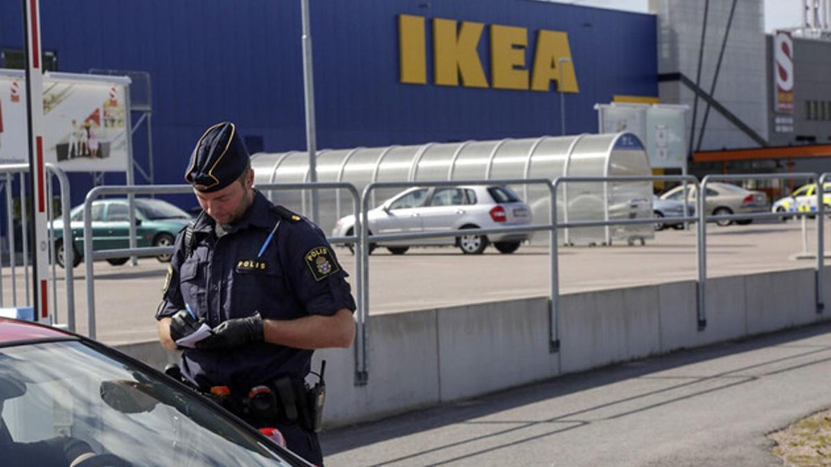 Un agente habla con unos clientes en las afueras del Ikea de Vasteras, en Suecia.