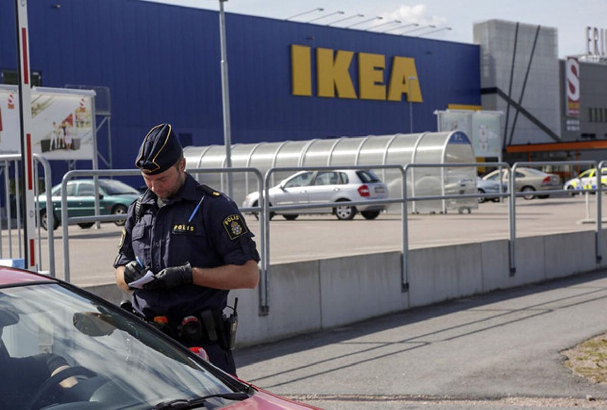 Un agent parla amb uns clients als afores de l’Ikea de Vasteras, a Suècia.
