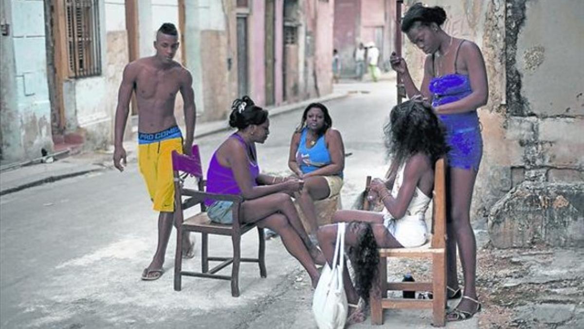 Una peluquera cubana atiende a una de sus clientas en plena calle de La Habana.