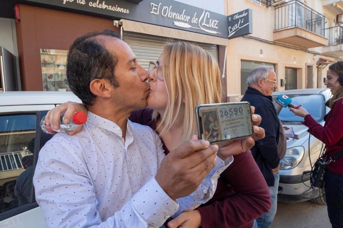 Los agraciados con un número del Gordo de Navidad Yesica Garcia y Alexander Zambrano se besan monstrando el número premiado en Murcia.