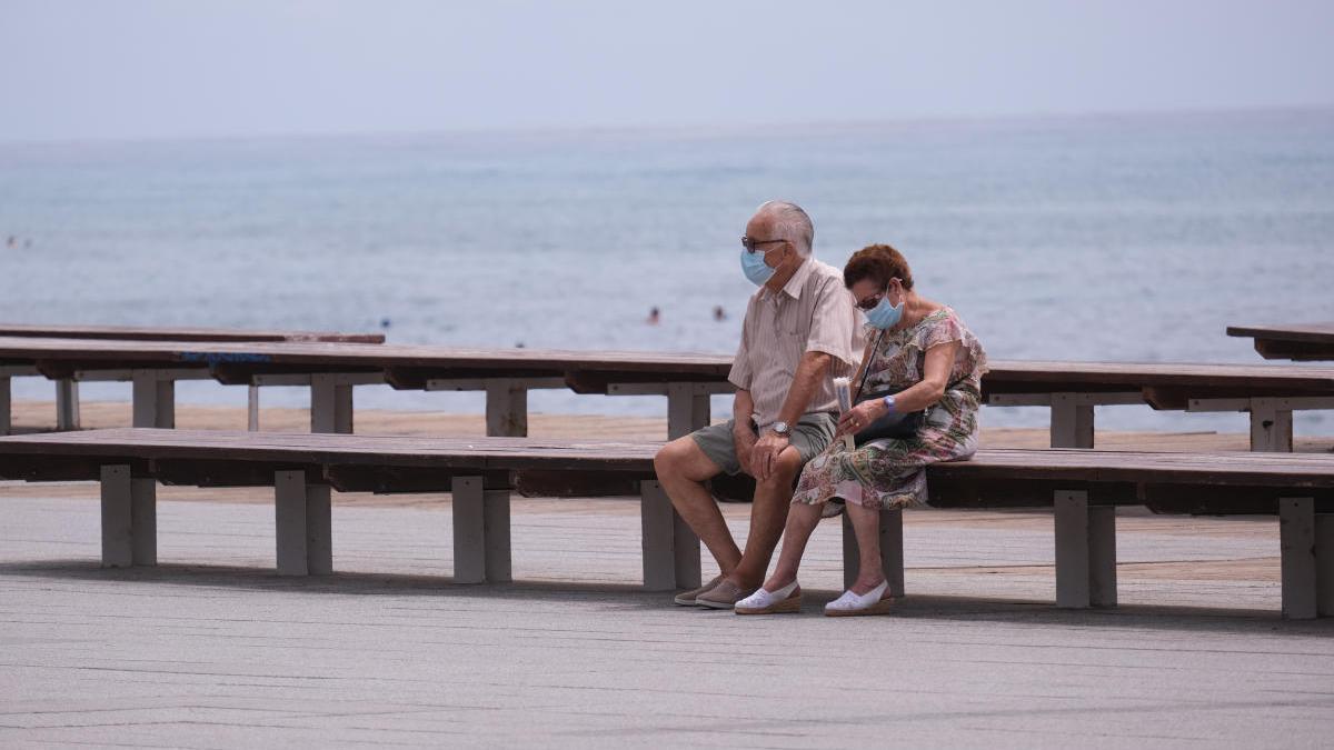 Una pareja descansa en un paseo marítimo alicantino.