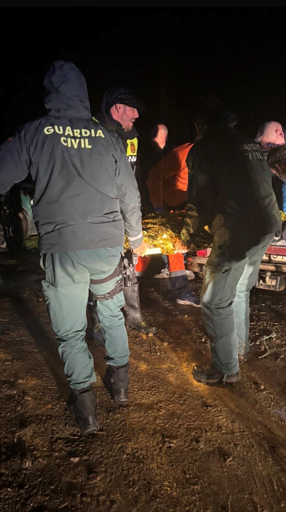 Guardias civiles, policías locales trasladan al herido tras rescatarlo en su finca de Adamuz.
