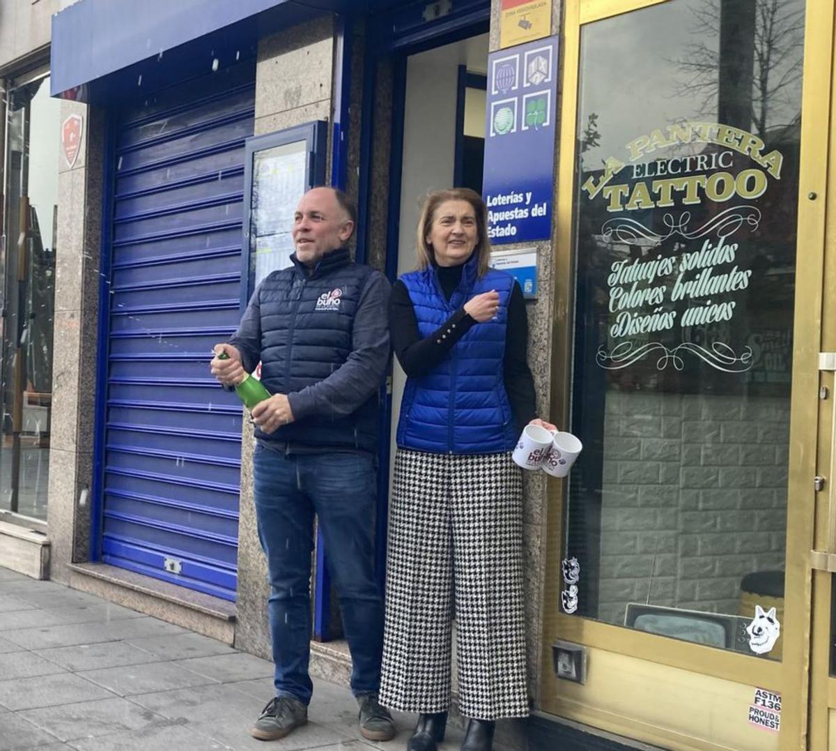 Los dos loteros descorchan una botella de sidra para celebrar los dos décimos repartidos en la calle Palacio Valdés. | P. P.
