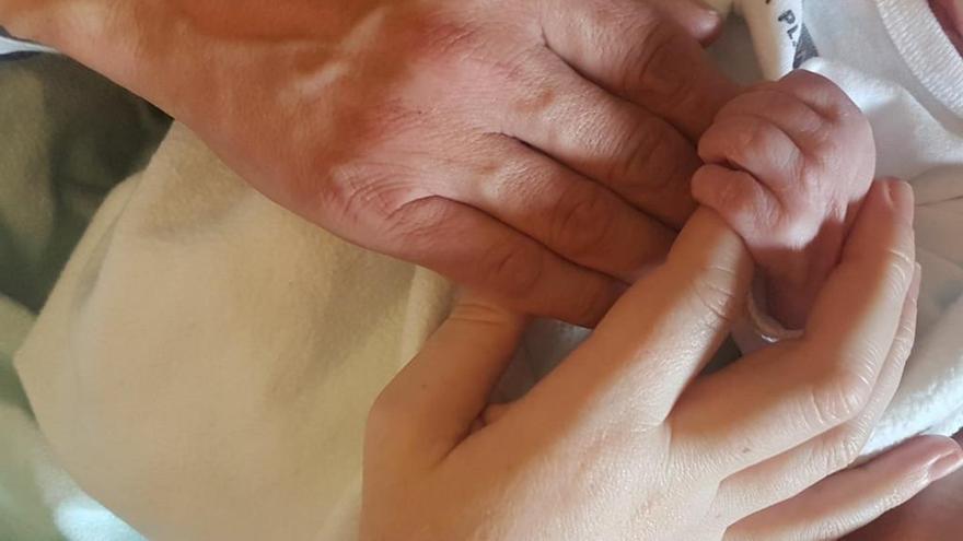 Las manos de los padres cogen las del recién nacido.