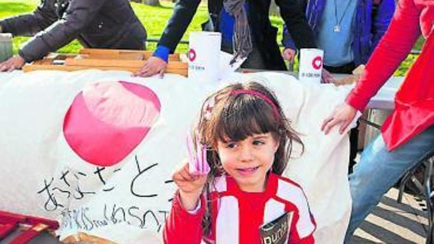 Una pequeña sportinguista muestra una grulla de origami, recibida tras dar un donativo en apoyo del pueblo japonés.