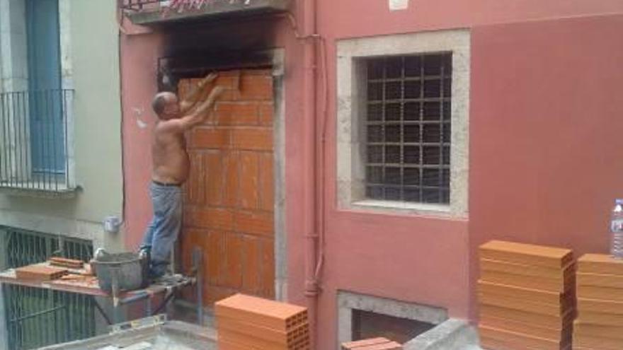 Un home tapia un pis del Barri Vell perquè no hi entrin okupes.