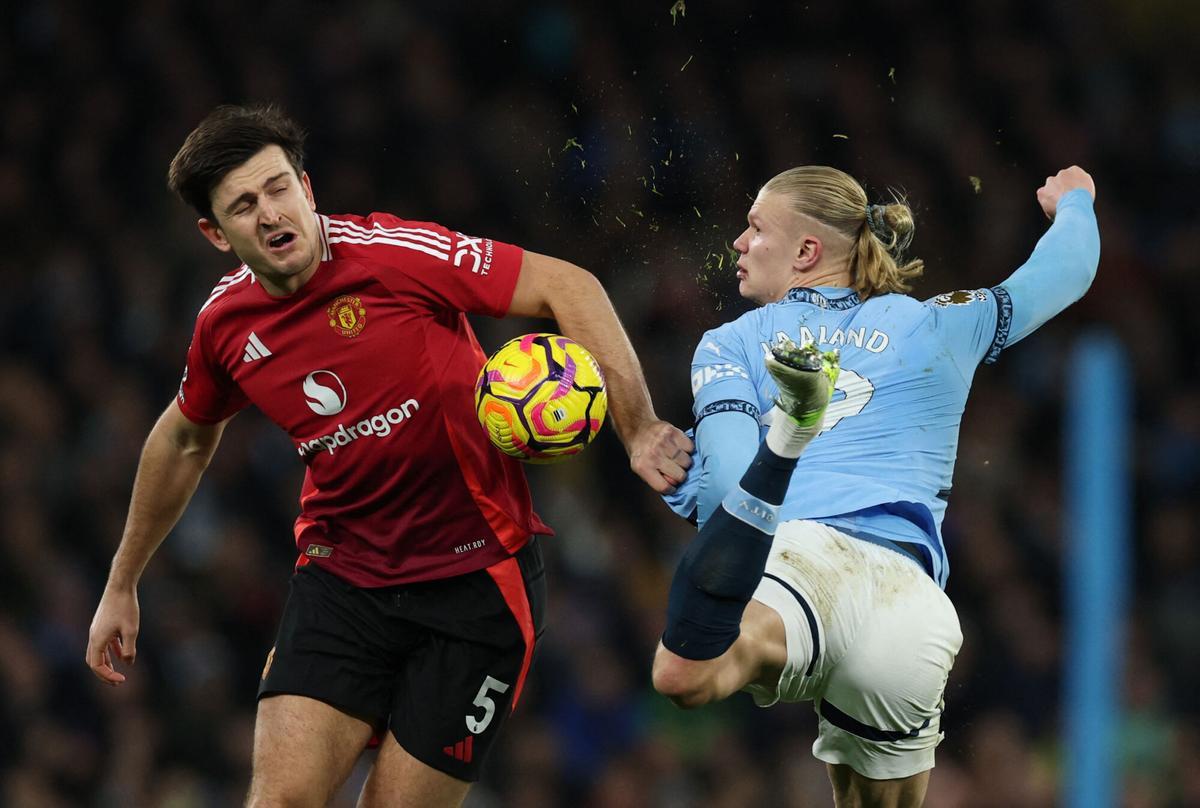 Erling Haalsn intenta tocar un balón que se lleva Harry Maguire.