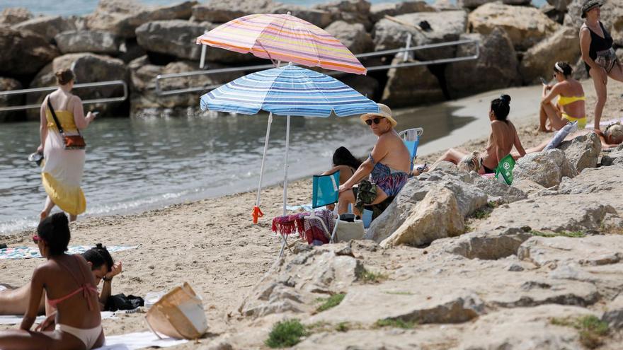 Varias personas se protegen del sol en la playa de ses Figueretes. | TONI ESCOBAR