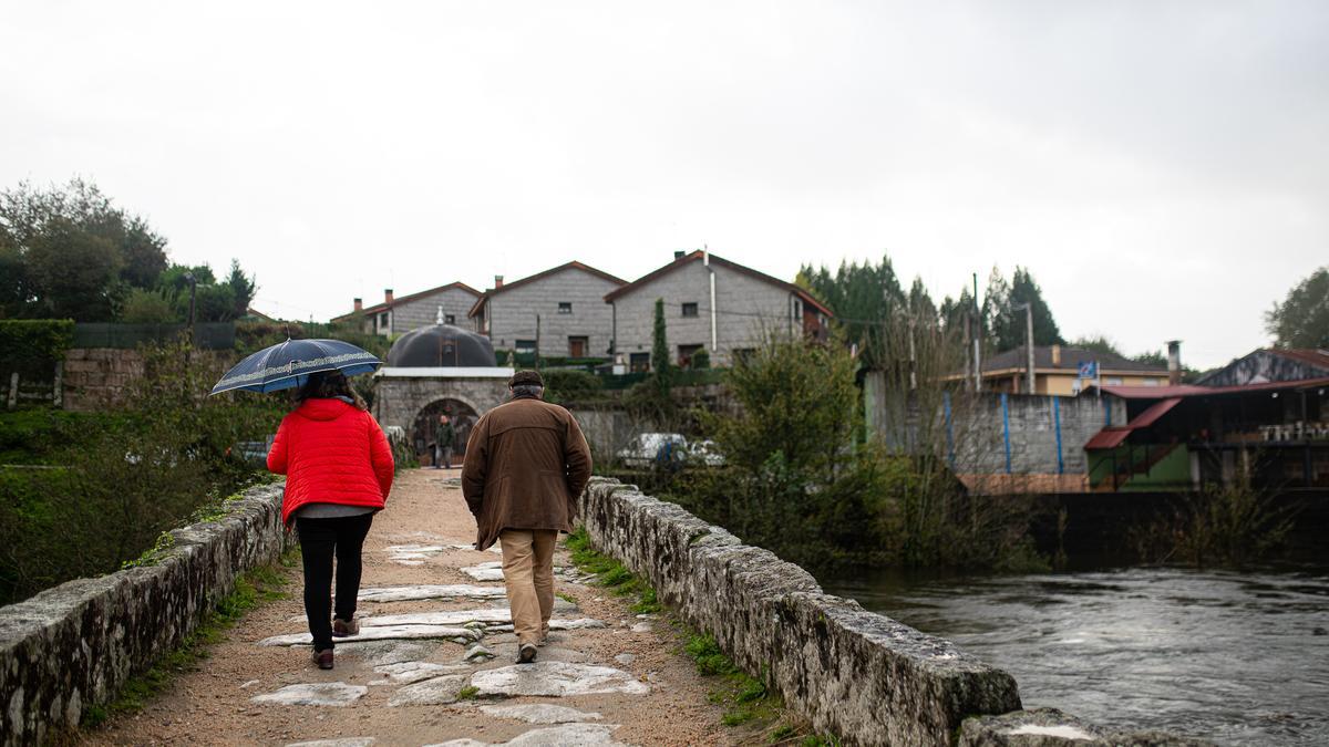 Varias personas cruzan un puente observando la crecida del río Tea, a 4 de noviembre de 2023, en Ponteareas, Pontevedra, Galicia (España).