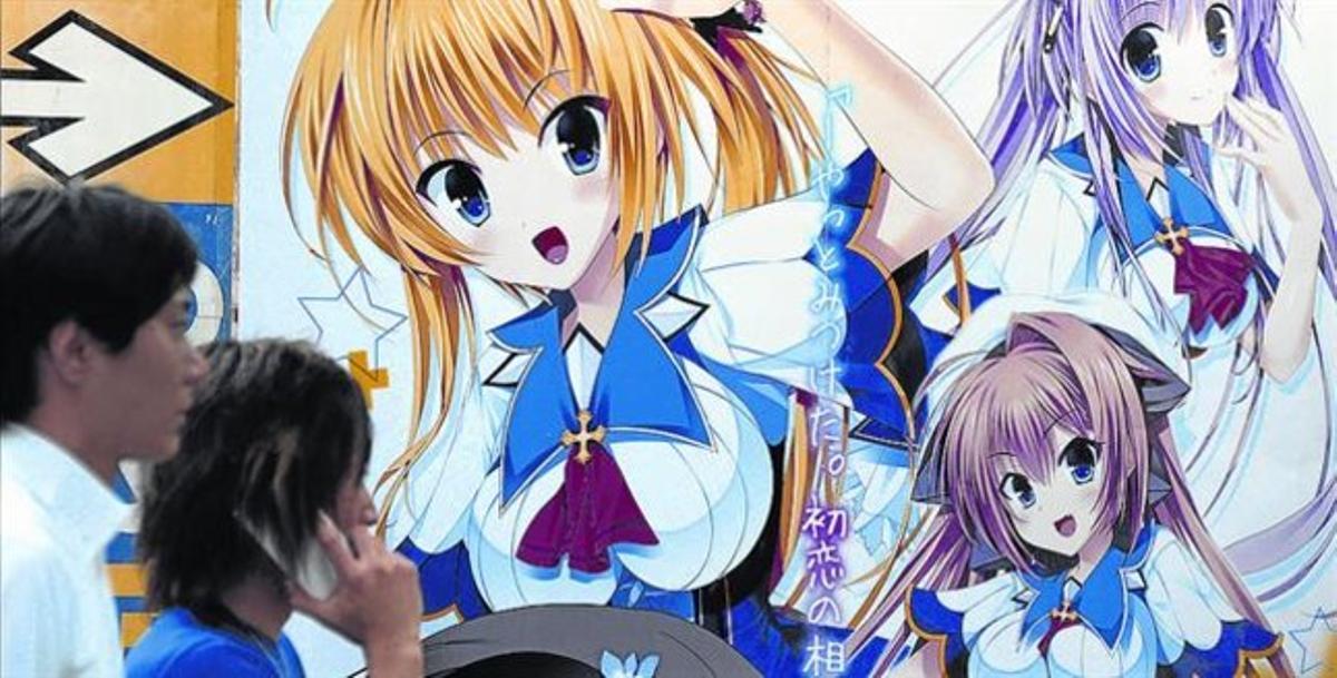 Uns vianants passen davant d’un dibuix manga en una paret d’un edifici de Tòquio. Uns vianants passen davant d’un dibuix manga en una paret d’un edifici de Tòquio.