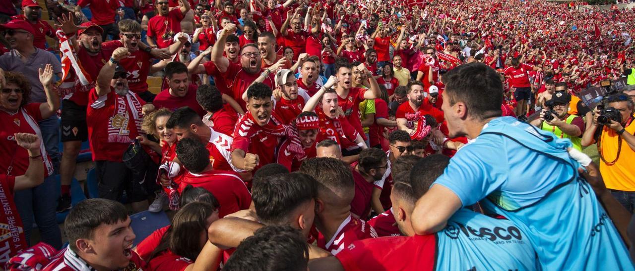 Los jugadores del Real Murcia se funden en un abrazo colectivo con sus aficionados para celebrar su salto a Primera RFEF, once años después de su último ascenso.