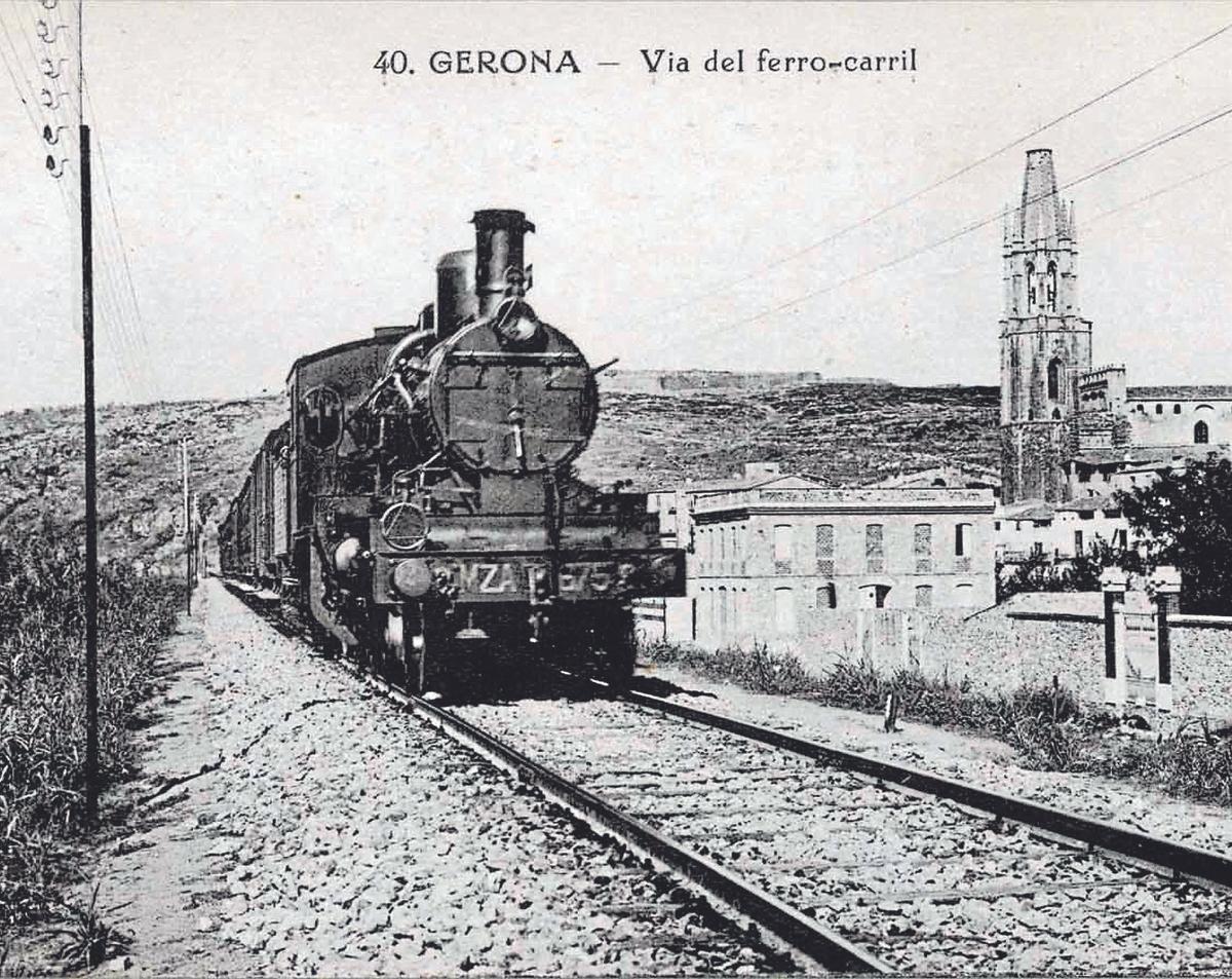 Una postal antiga que mostra un tren circulant a l'alçada de Girona, amb l'Església de Sant Feliu de fons.