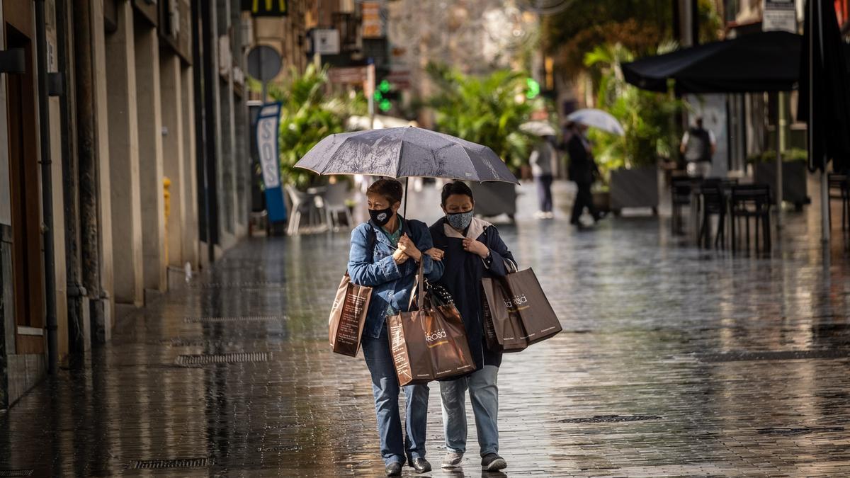 Dos mujeres andan bajo la lluvia santacrucera.