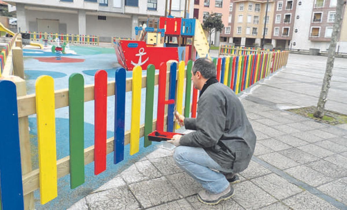 Pablo González, de la empresa Asturmadera, terminando de pintar ayer el vallado del parque.