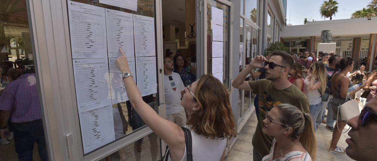 Aspirantes a convertirse en funcionarios miran los listados antes de realizar el examen.