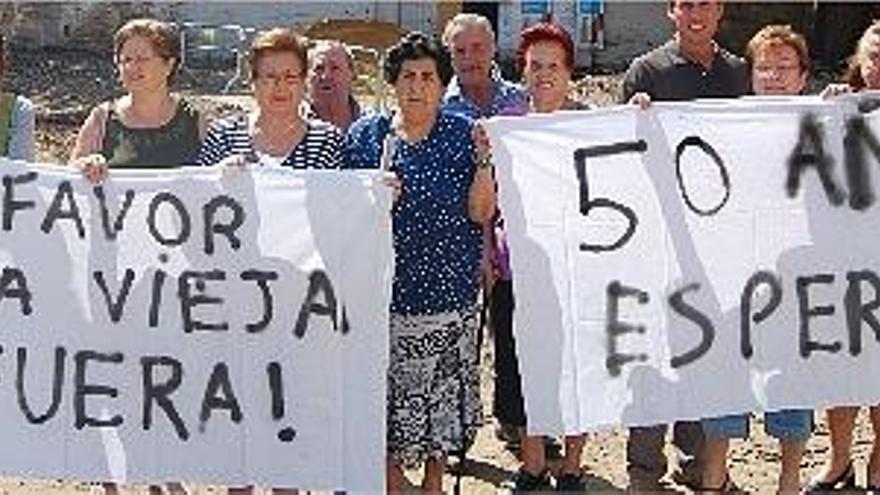 Un grupo de vecinos muestra sus pancartas ante la casa que quieren que sea derribada en una protesta, ayer.