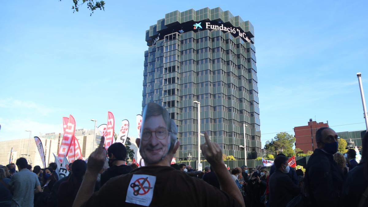 Un treballador de CaixaBank amb una mascareta del president de l&#039;entitat, José Ignacio Goirigolzarri, davant la seu de la fundació La Caixa a la Diagonal de Barcelona