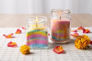 Velas en tarros de arena de colores.