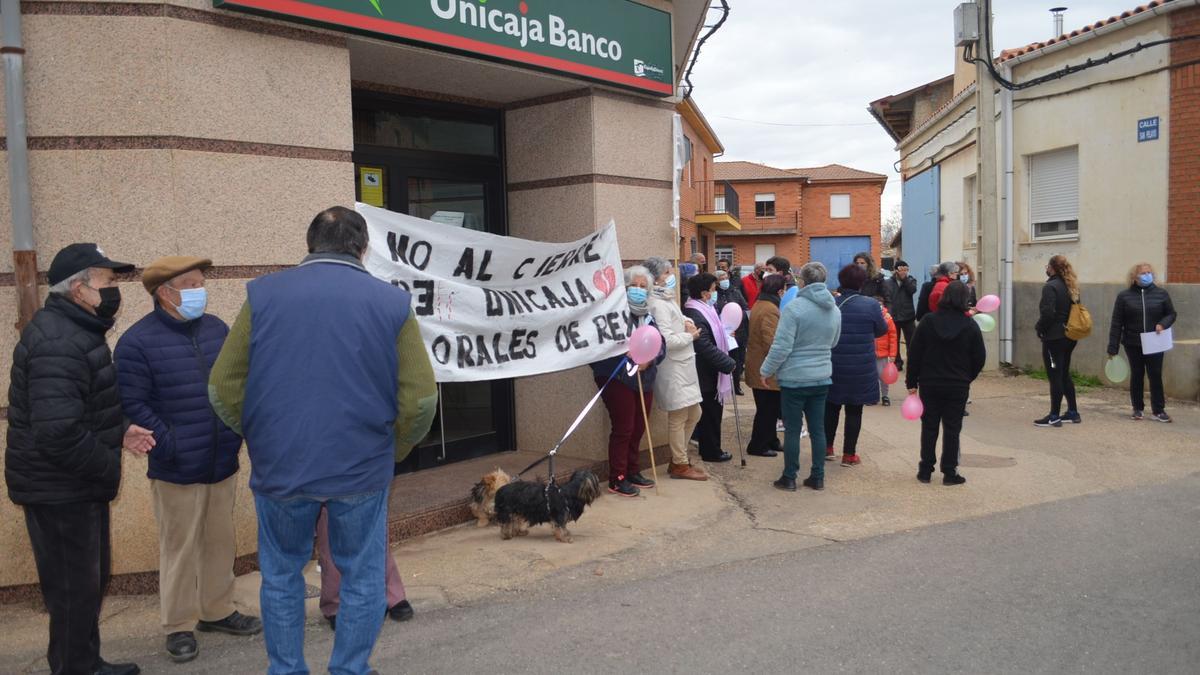 Vecinos de Morales de Rey y Vecilla ante la oficina de Unicaja para protestar por su cierre. / E. P.