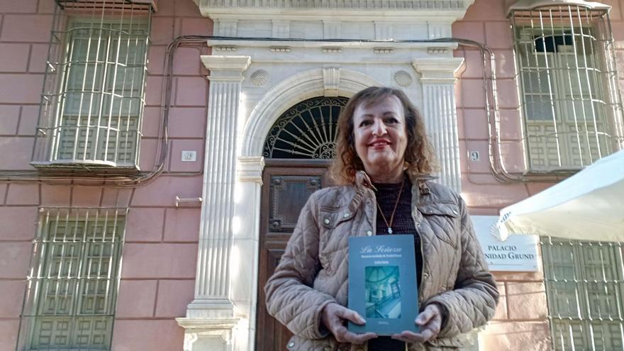 La escritora malagueña, con su novela sobre Trinidad Grund delante del palacio en eel que vivió, en la hoy calle Trinidad Grund.