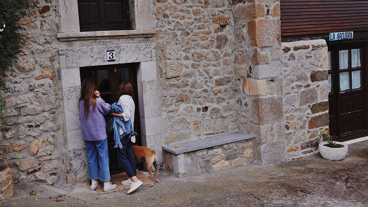 Dos mujeres acuden ayer por la tarde a la vivienda de Sardéu (Ribadesella) donde residía Menchu Álvarez del Valle.