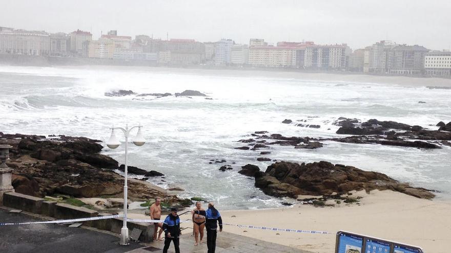 En la playa de Riazor la Policía Local desaloja, ayer, a dos bañistas.