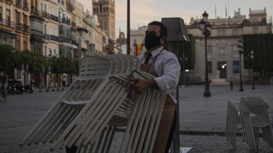 Un hostelero recoge el mobiliario de la terraza de un bar.